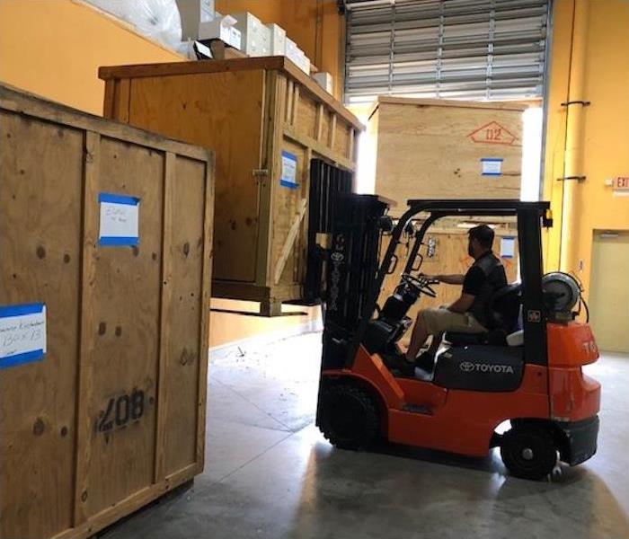 SERVPRO employee driving a forklift moving wooden crates